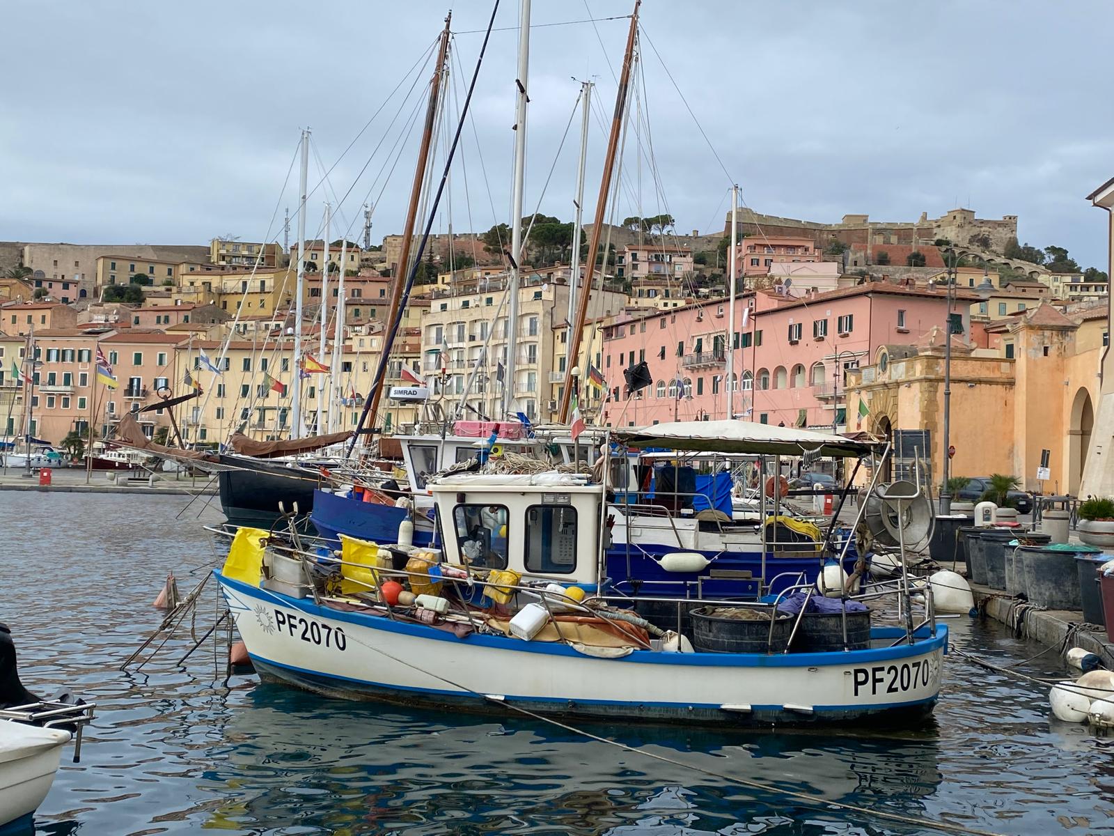 Fischerboot im Hafen einer italienischen Küstenstadt mit bunten Häuserfronten
