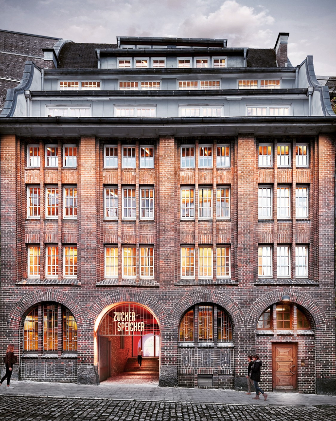 Fassade des Zuckerspeichers in der Haßstraße — Backsteinbau mit beleuchtetem ZUCKER-SPEICHER-Torbogen im Abendlicht